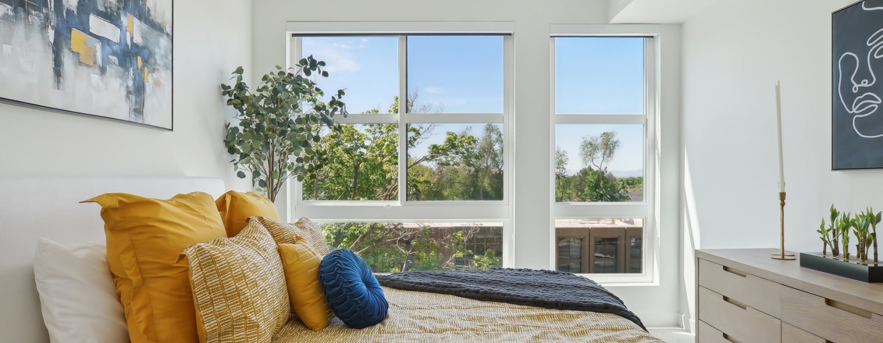 Liberty Duet Apartments, Salt Lake City Utah, bedroom with a large window, bed with pillows in yellow shades, dresser