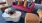 Liberty Duet Apartments, Salt Lake City, Utah, rooftop lounge, dark pink sofa with tan and blue pillow, marble coffee table with plant and tray, additional tan chairs. 