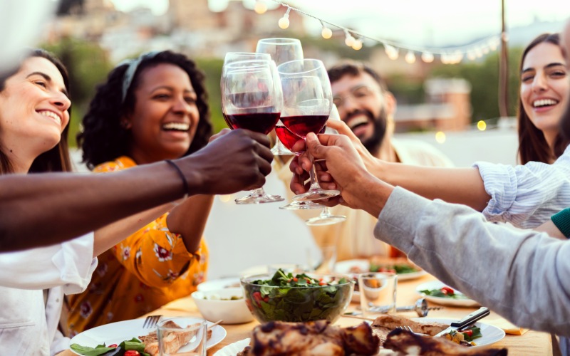 group toasting with wine over a full table of food