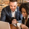 multiracial couple drinking coffee and working on laptop